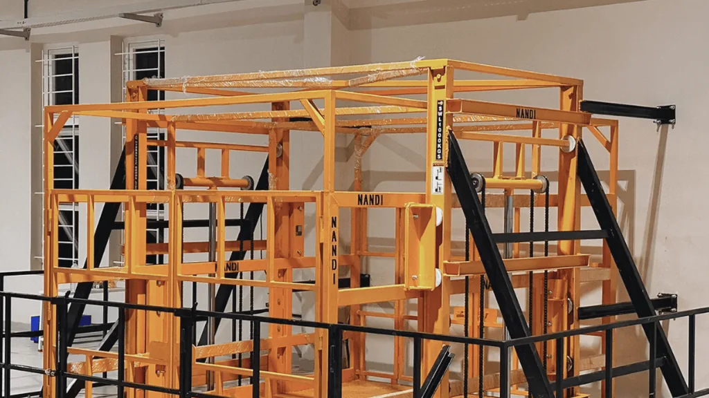 A Nandi double-mast hydraulic goods lift cage installed at a mezzanine in an industrial unit
